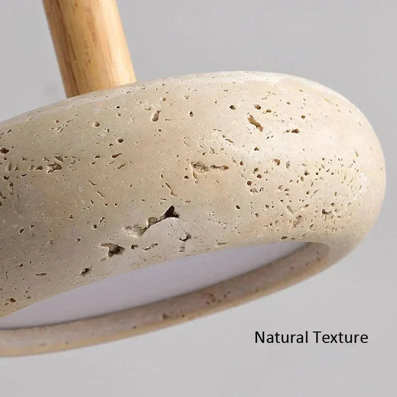 Close-up of a textured stone lamp base in a natural beige color with a light wood stem, showing the porous stone surface and the text 'Natural Texture' on a neutral gray background.