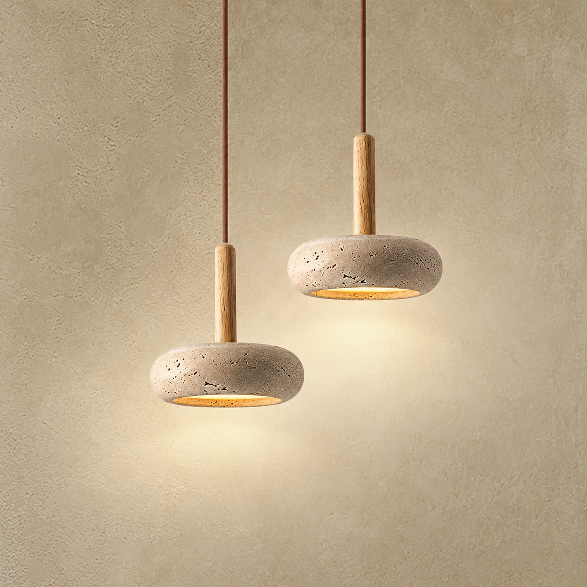 Two modern pendant lights with textured stone shades and light wood stems, suspended against a warm beige plaster wall.