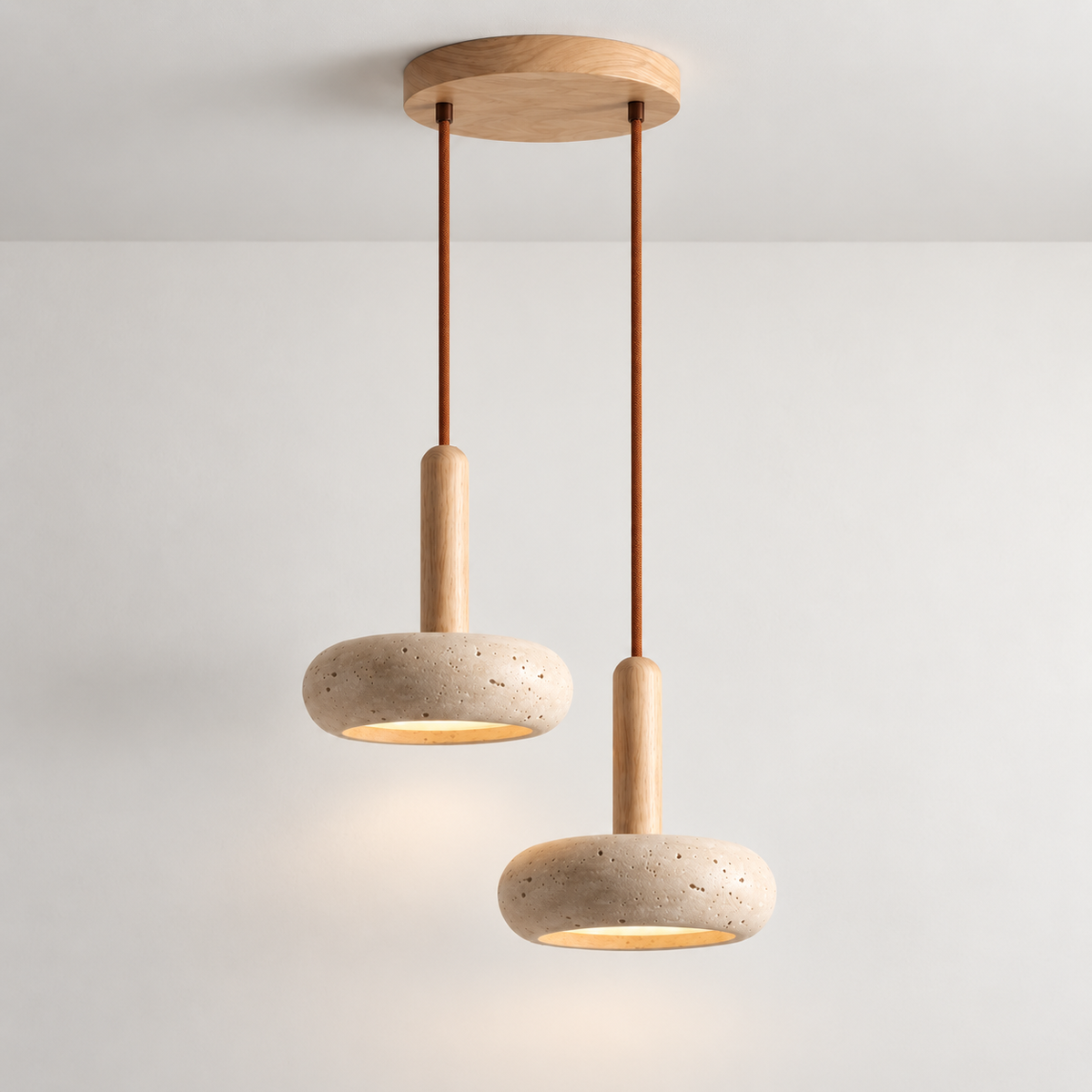 Two travertine stone pendant lights on one round wood ceiling plate, hung at staggered lengths on brown cords.