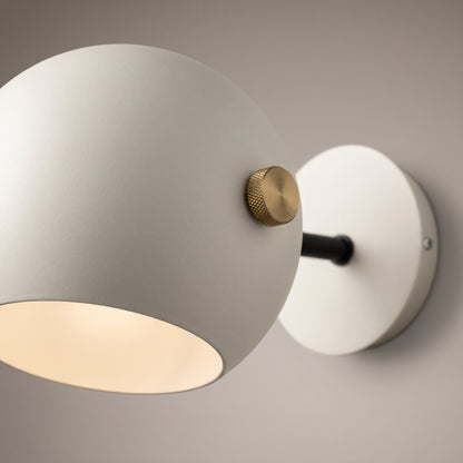 Close-up of the ball wall lamp showing the matt powder-coated shade, cream painted interior and knurled brass pivot knob