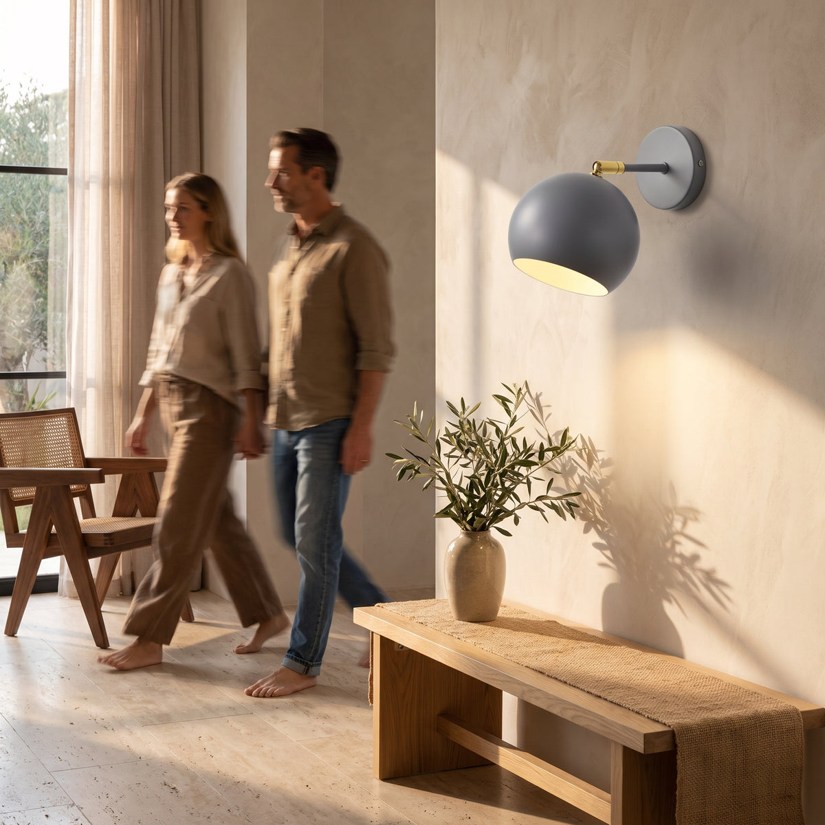 Grey ball wall lamp lighting an entryway wall above a light oak bench in a limewash plaster hallway