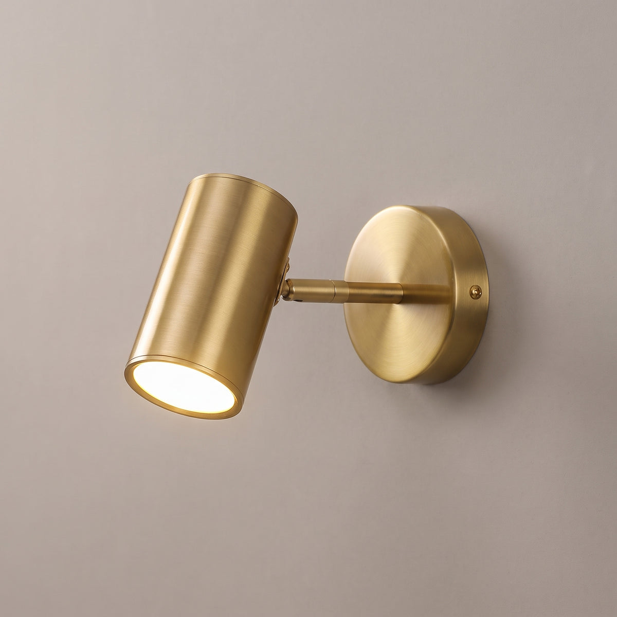 Gold finish option: adjustable wall spot light with a brushed brass cylinder head, arm and round wall plate