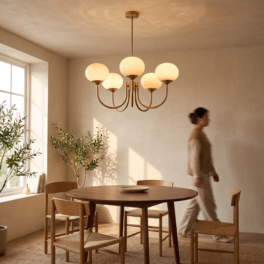 Beige five-dome Bauhaus glass chandelier on brass arms above a round walnut dining table in a warm limewash dining room