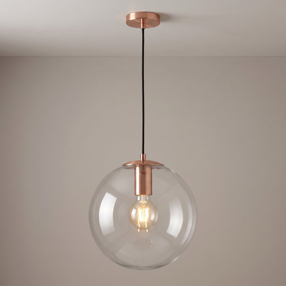 Rose gold finish option: clear glass globe pendant light with a brushed copper collar and ceiling canopy