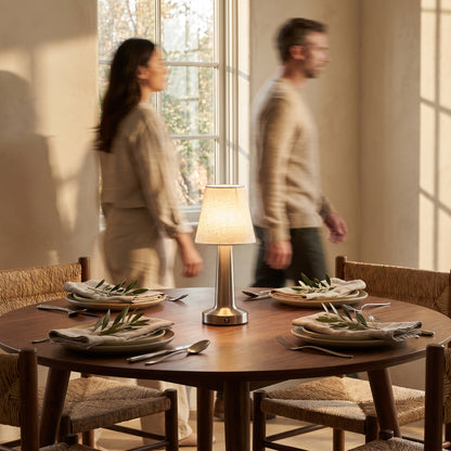 Cordless linen table lamp standing in the middle of a set walnut dining table with rush-seat chairs