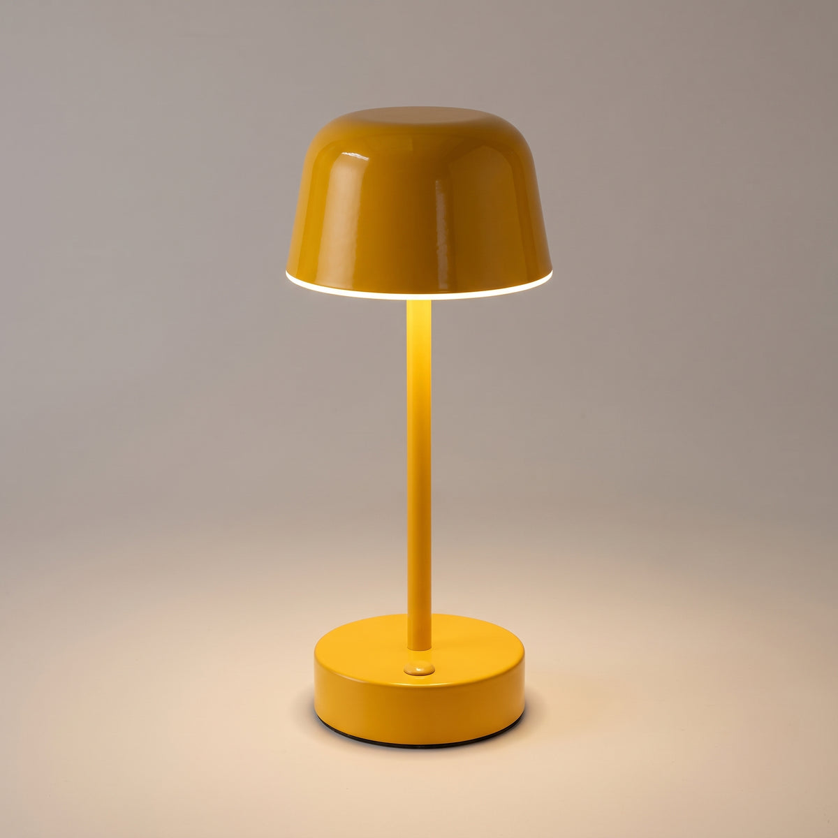 Close-up of the yellow mushroom table lamp showing the glossy painted cap, the ring of warm light beneath it and the button on the base