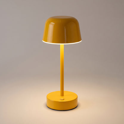 Close-up of the yellow mushroom table lamp showing the glossy painted cap, the ring of warm light beneath it and the button on the base