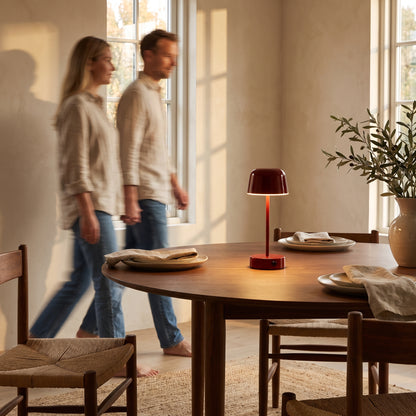 Red cordless mushroom table lamp standing in the middle of a set walnut dining table
