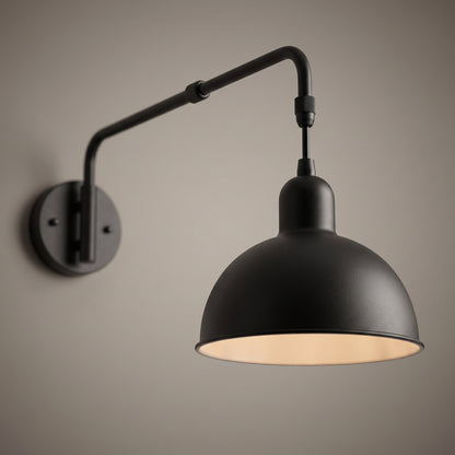 Close-up of the swing arm wall light showing the telescopic collar, the elbow joint and the warm painted inside of the dome shade