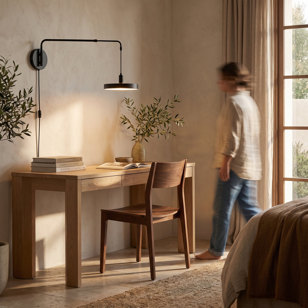 Swing arm wall light with the flat disc shade extended over a light oak desk in a home office corner