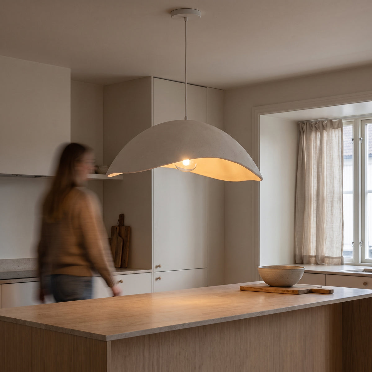 White wabi-sabi pendant light hanging low over a pale oak kitchen island