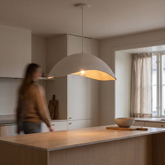 White wabi-sabi pendant light hanging low over a pale oak kitchen island