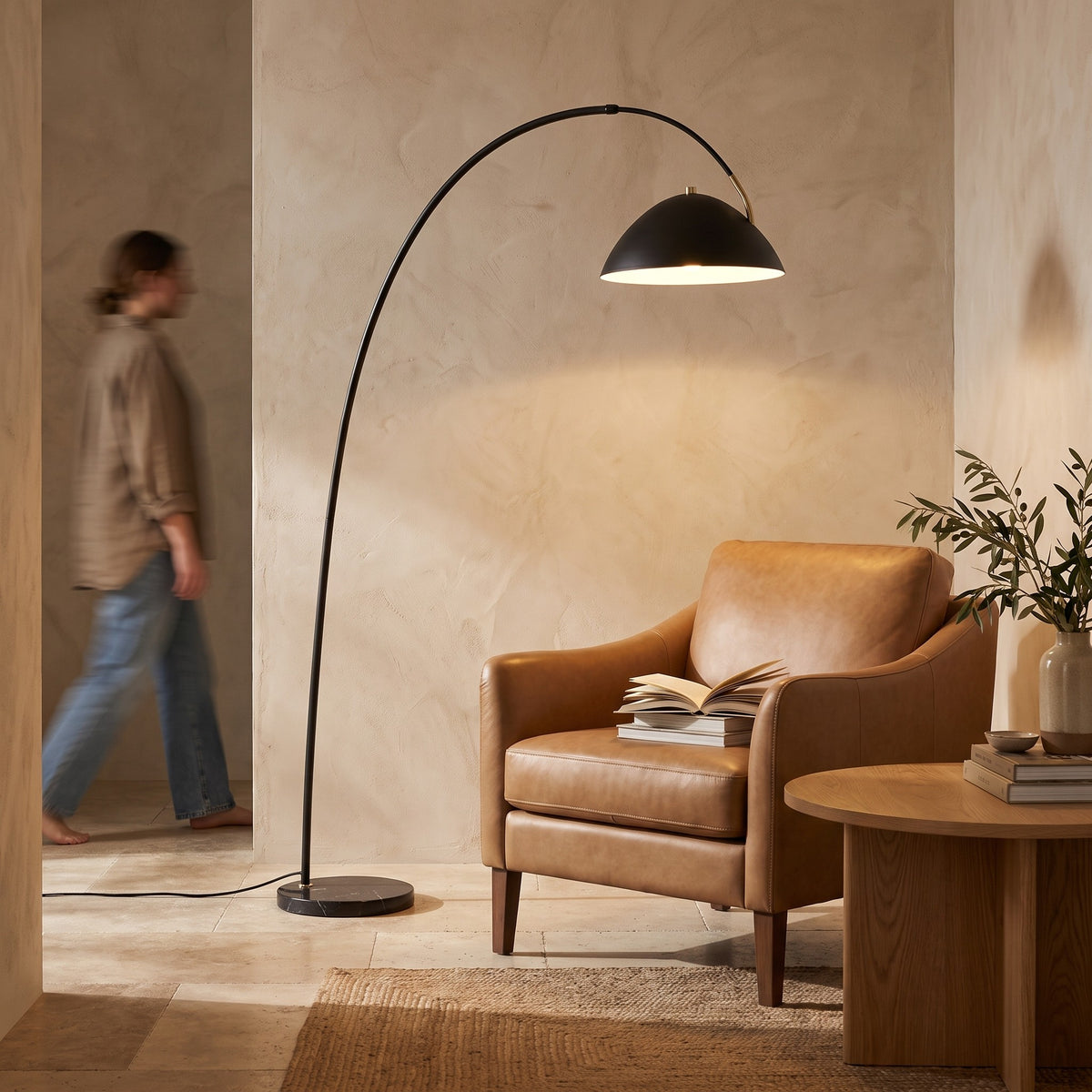 Arc floor lamp lighting a leather reading chair and side table with books