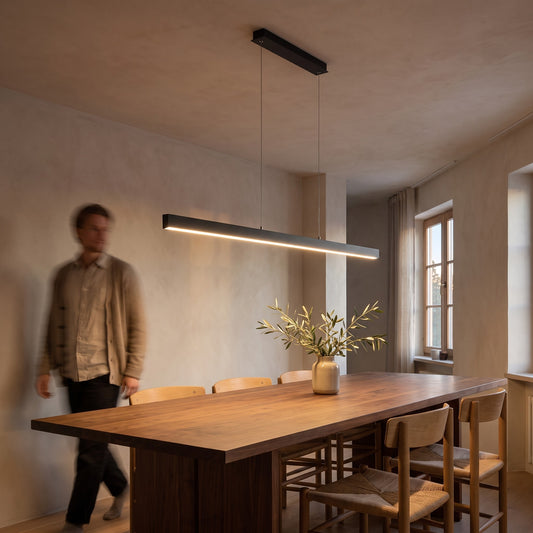 Black linear LED pendant lighting a long walnut dining table