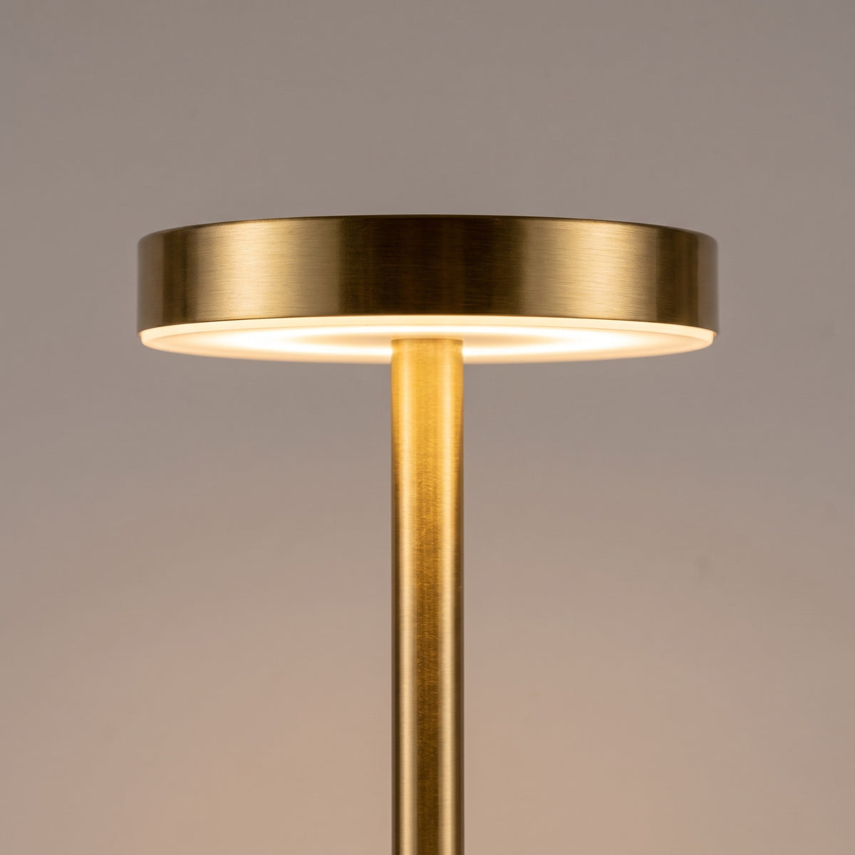 Close up of the brushed gold top disc and LED ring of the slim cordless lamp