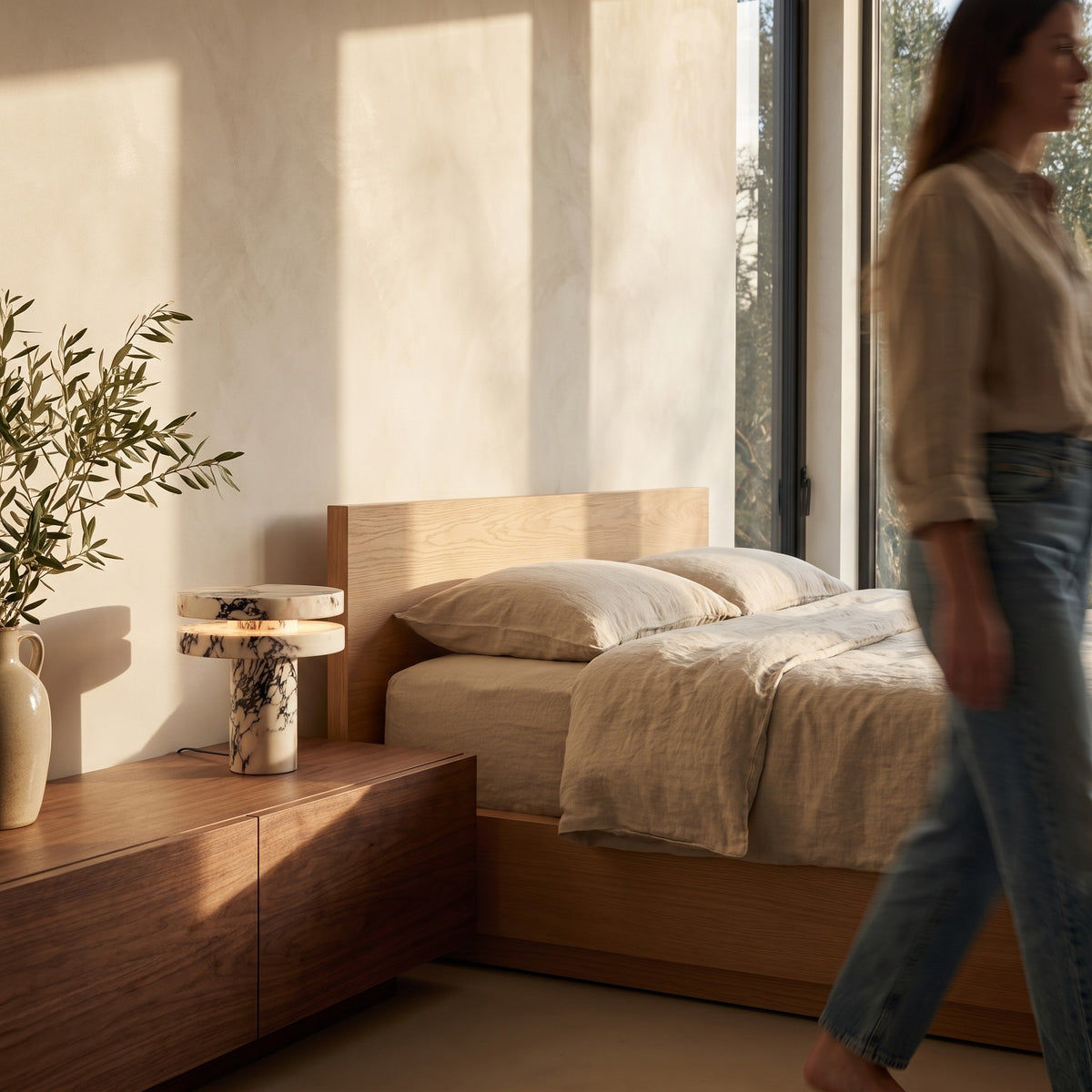 Marble table lamp on a walnut nightstand beside a linen bed in the evening